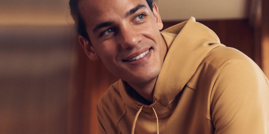 Mężczyzna uśmiechający się podczas noszenia musztardowej żółtej Bluzy Z Kapturem.