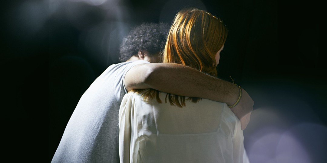 czarny mężczyzna z ramieniem na ramieniu rudowłosej kobiety.