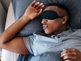 Mężczyzna noszący nocną maskę i śpiący w swoim łóżku w domu