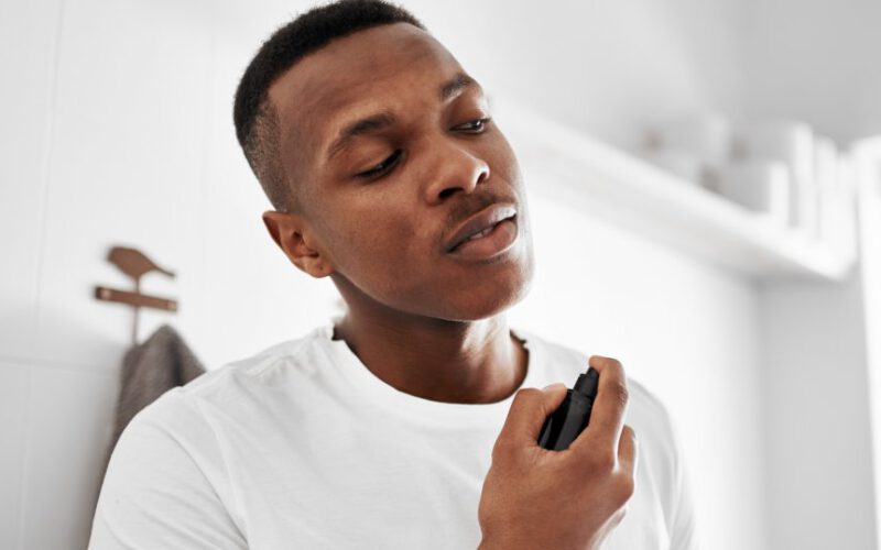 Ujęcie młodego mężczyzny natryskującego się dezodorantem
