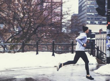 Biegacz jogging w centrum miasta na ulicy w Zimowy dzień ze śniegiem w tle