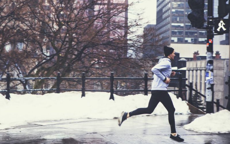 Biegacz jogging w centrum miasta na ulicy w Zimowy dzień ze śniegiem w tle