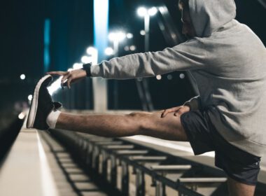 Zdeterminowany sportowiec wyciągający Nogi na moście w nocy.