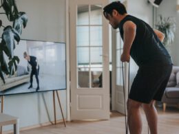 Mężczyzna biorący zajęcia fitness na tym telewizorze w domu