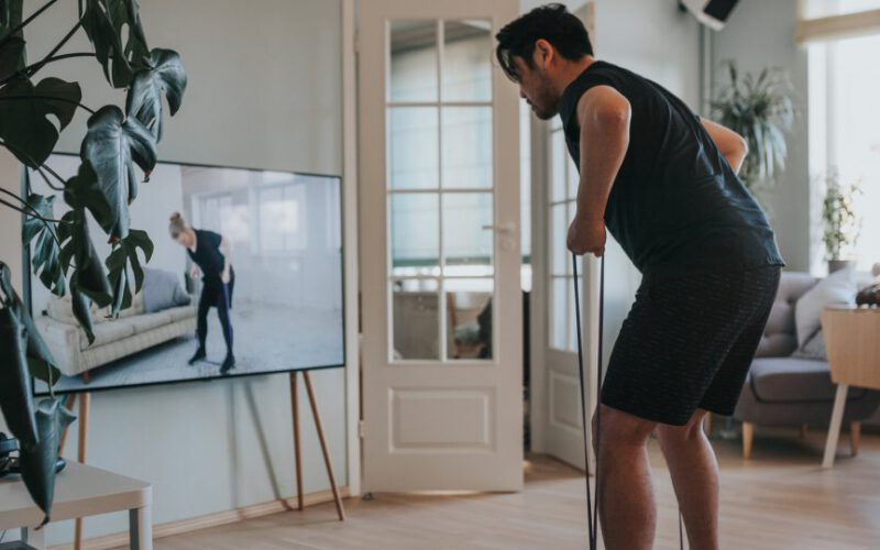 Mężczyzna biorący zajęcia fitness na tym telewizorze w domu
