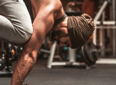 Mężczyzna robi Kruk (Bakasana) Joga pozować w a siłownia