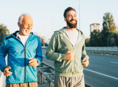 Szczęśliwy ojciec i syn jogging razem Na zewnątrz wzdłuż dużego nowoczesnego mostu.