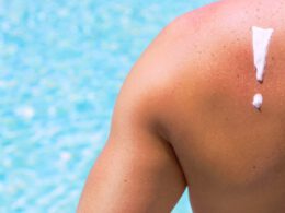 Widok pleców mężczyzny z filtrem przeciwsłonecznym w kształcie wykrzyknika, mężczyzna siedzący przed basenem