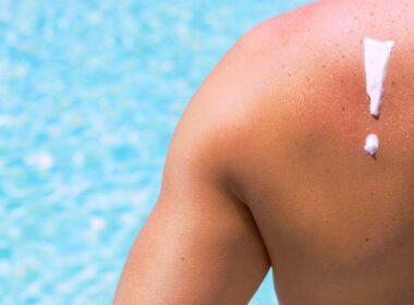 Widok pleców mężczyzny z filtrem przeciwsłonecznym w kształcie wykrzyknika, mężczyzna siedzący przed basenem