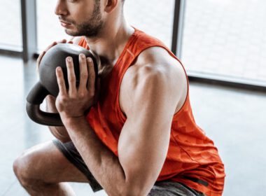 Mężczyzna robi trening przysiadowy, trzymając kettlebell