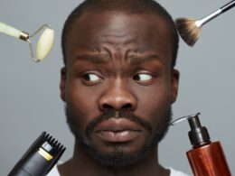 Czarny człowiek z mylić wygląd podczas różnych narzędzi do pielęgnacji skóry najbliższych na jego twarzy