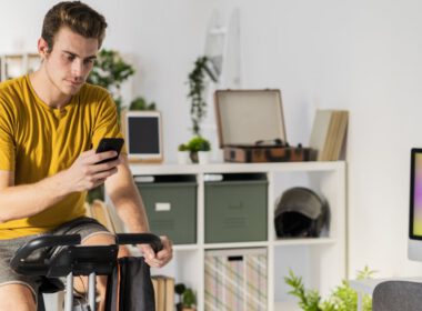 Człowiek za pomocą telefonu komórkowego podczas jazdy na rowerze na sprzęt do ćwiczeń w domu