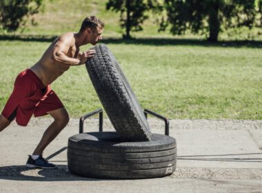 Mężczyzna ćwiczy, pchając dużą oponę Na Zewnątrz