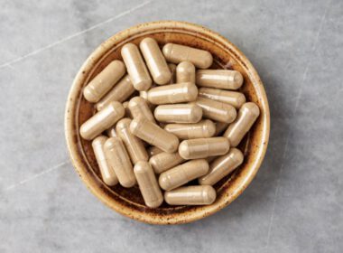 Ashwagandha (Withania somnifera) kapsułki w misce na jasnym kamiennym blacie