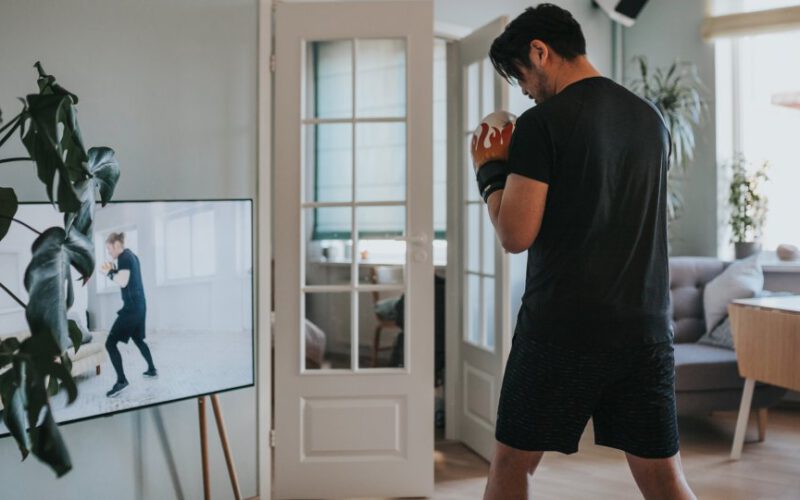 Mężczyzna podążający wraz z treningiem bokserskim na telewizorze w domu