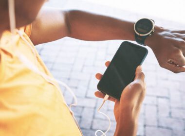 Ujęcie mężczyzny parującego zegarek ze smartfonem podczas treningu na miejskim tle
