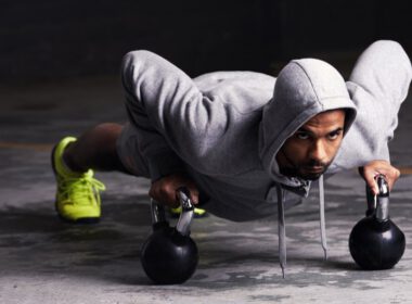 Mężczyzna w bluzie i robi pompki z kettlebell