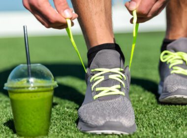 Zielony smoothie w trawie i mężczyzna tieing jego buty